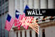 A Wall Street street sign with American flags in the backdrop