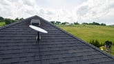 SpaceX Starlink satellite dish on a rooftop in the countryside.