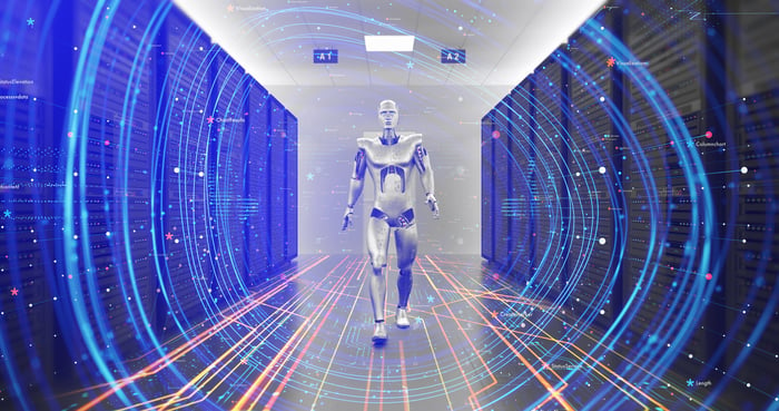 A humanoid robot walking down an aisle of a data center.