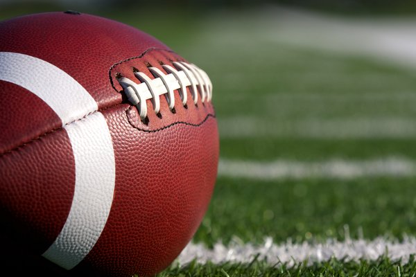 American football sitting on a football field.